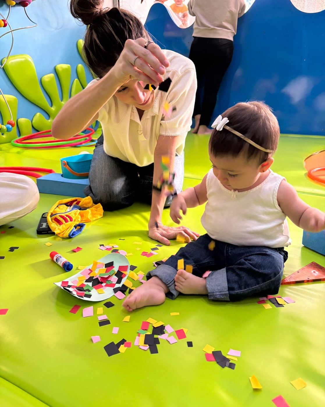 Mamá y bebé jugando con papel en el piso de Peces al Agua